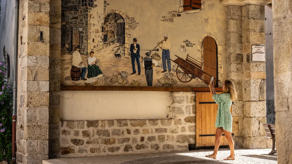 Femme photographiant une fresque du village de caractère de Thueyts
